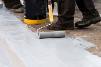 Roller applying a reflective roof coating