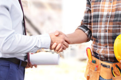 A businessman and a roofer shaking hands