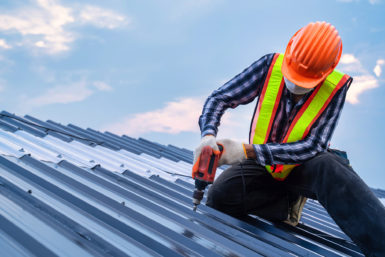 Roofer installing metal roof panels